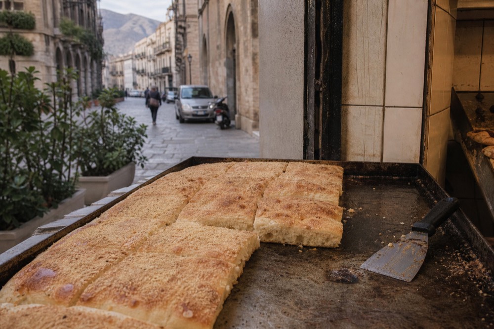 White sfincione cut into squares on a bakery tray