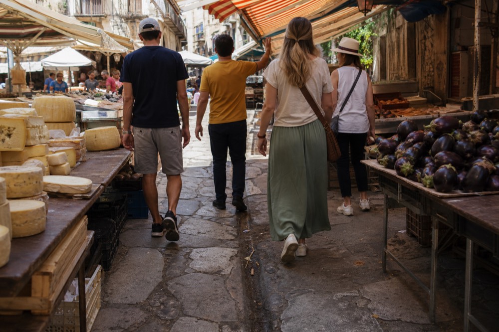A guide leading a small group between market stalls in Palermo