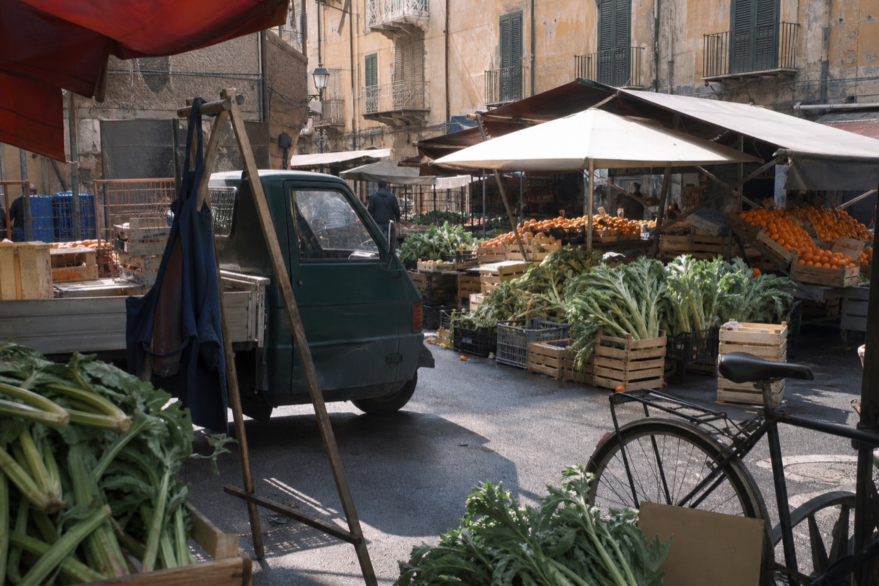 Stalls of fruit and vegetables under canvas awnings in a Palermo street market