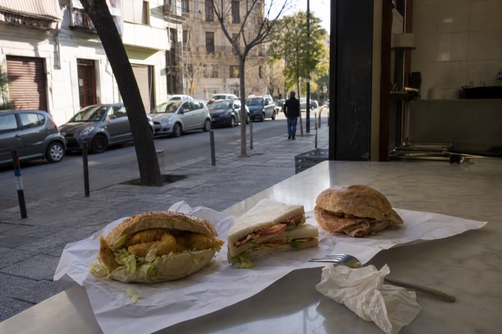 A selection of Italian sandwiches including a piadina, tramezzino, and porchetta roll on a counter