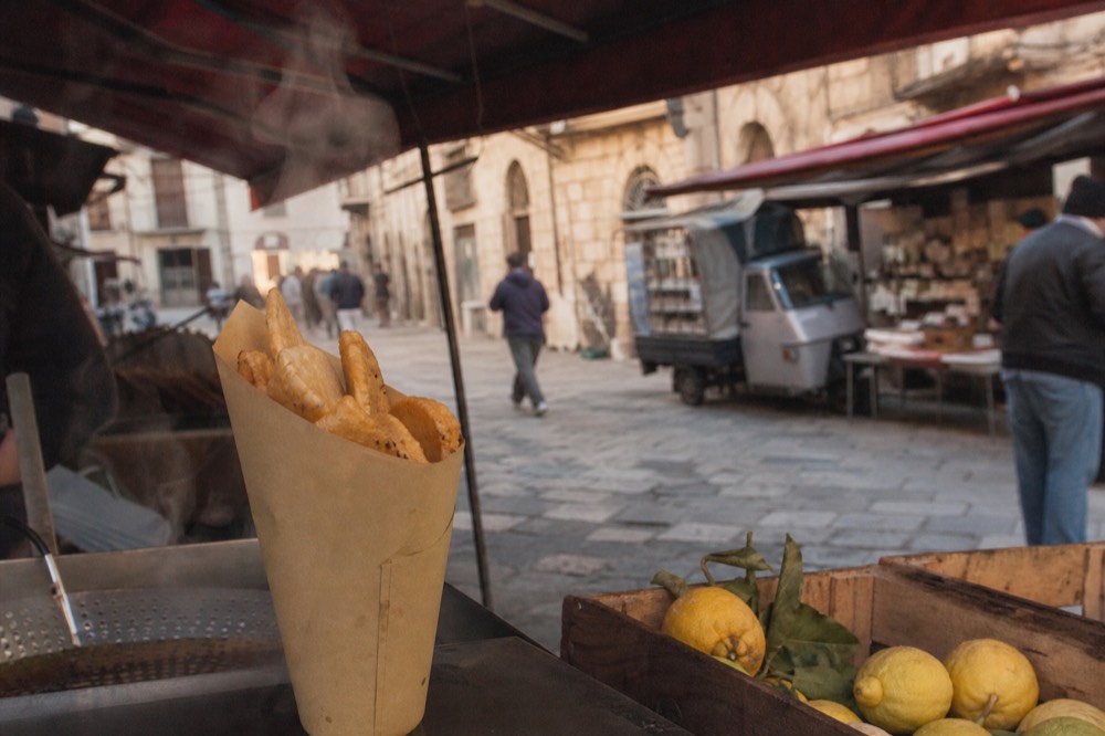 A paper cone of fried panelle on a market stall counter