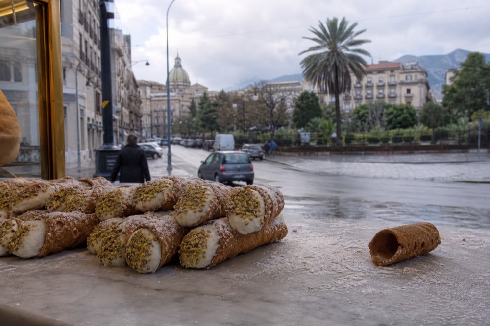 Sicilian cannoli filled with ricotta cream and pistachio on a pastry shop counter