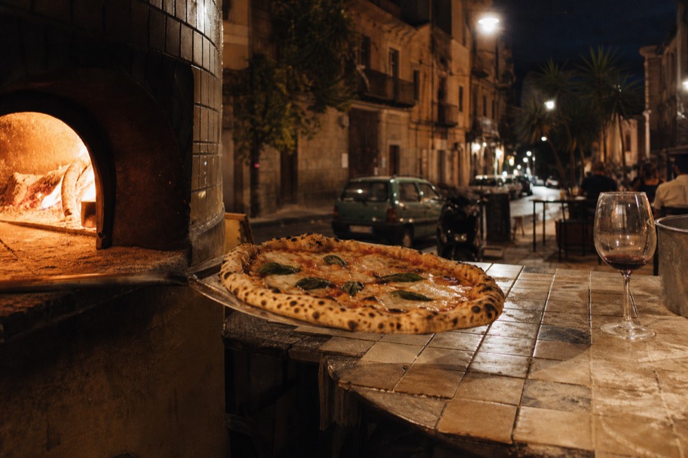 A wood-fired pizza fresh from the oven with blistered crust and fresh basil