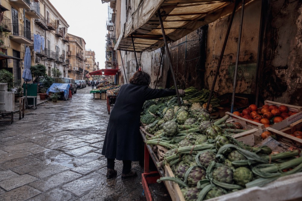 Market street with canvas awnings and crates of vegetables in Palermo