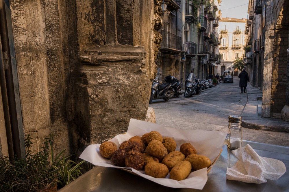 Fried chickpea fritters and potato croquettes served in a paper tray