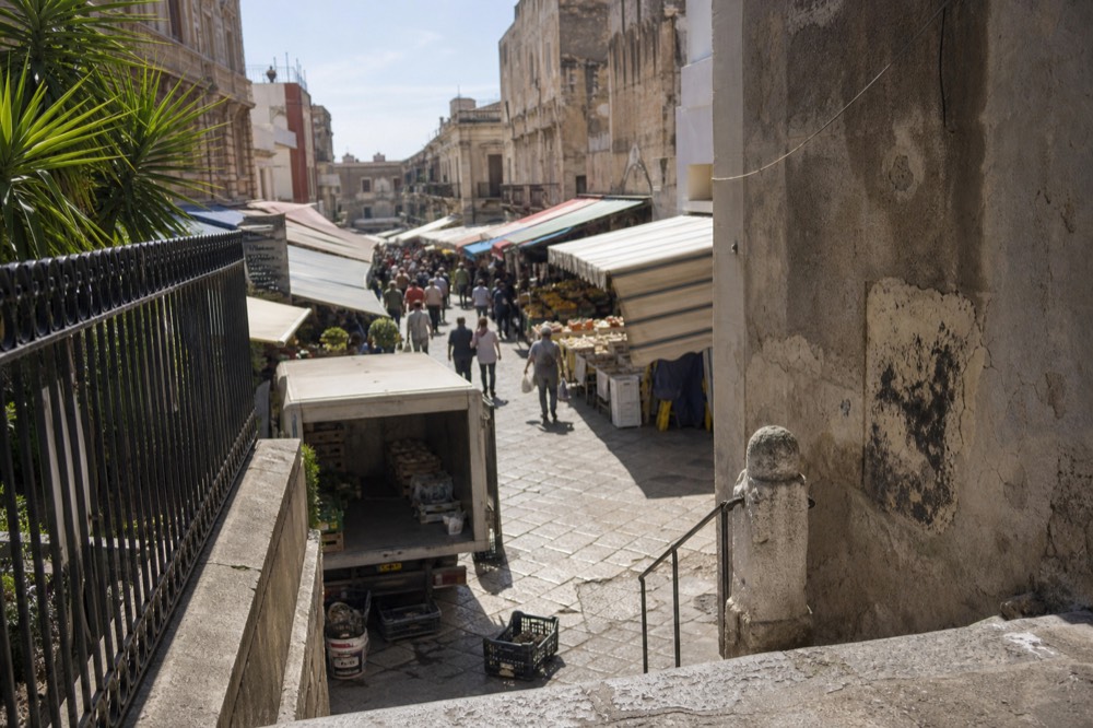 Narrow Palermo market lane lined with produce stalls under canvas awnings