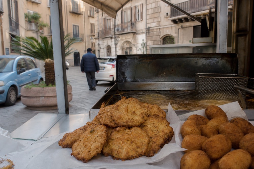 Fried chickpea fritters and potato croquettes on a market food stall counter