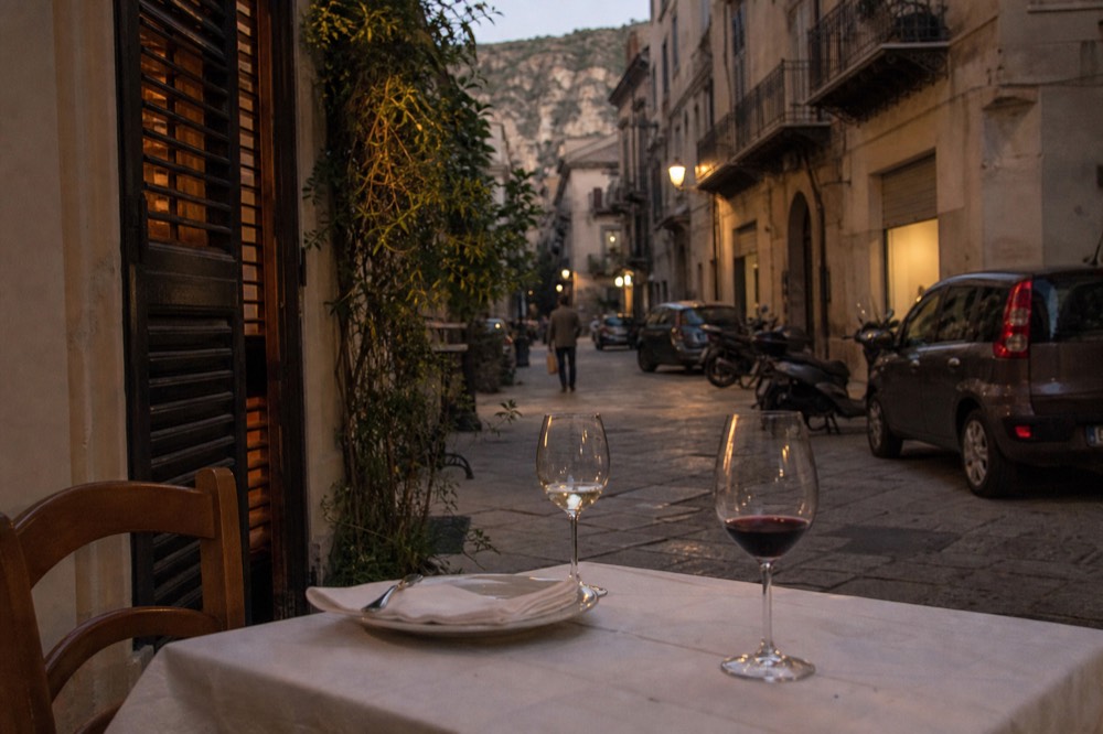 Set restaurant table with white tablecloth and wine glasses beside a tiled floor