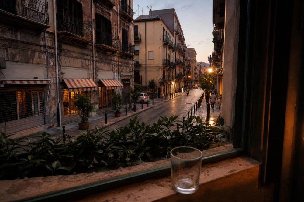 Narrow old street with balconied buildings and market awnings in a Sicilian city at dusk