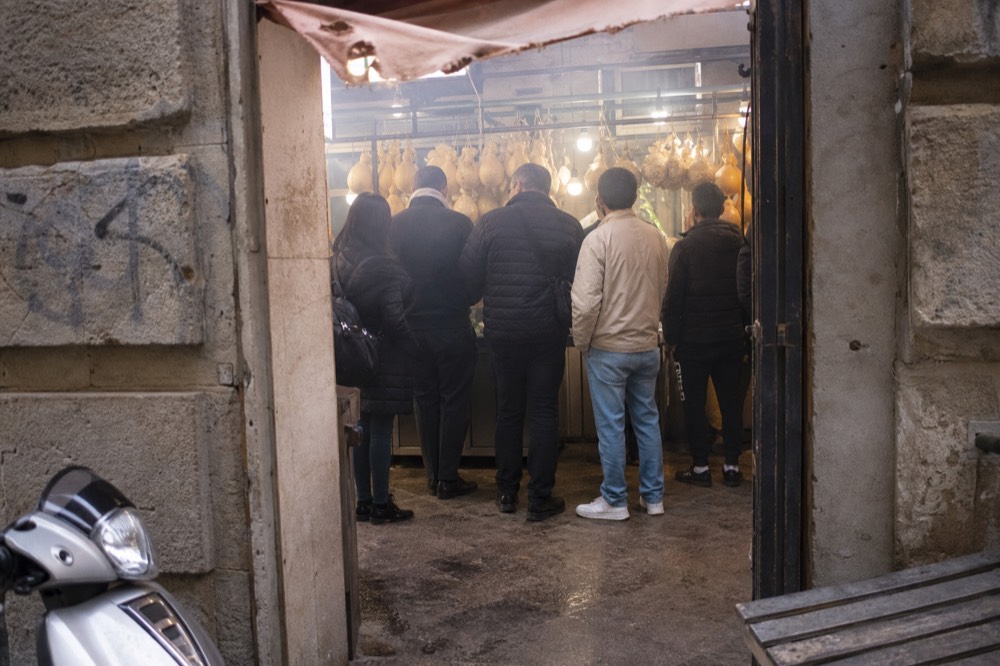A small group standing around a guide at a Palermo market stall
