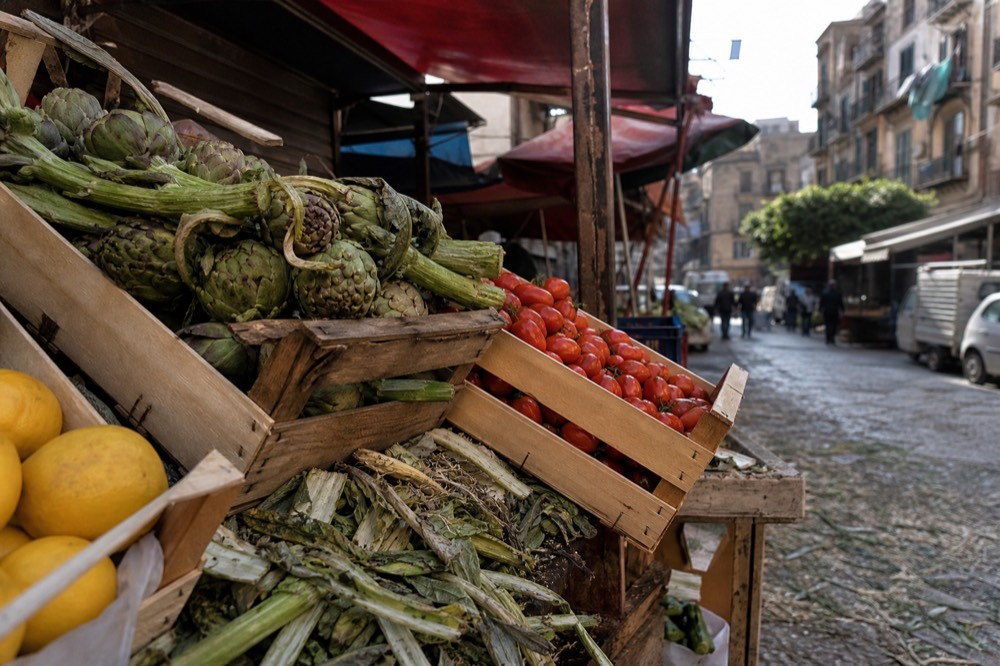 Wooden crates of artichokes, tomatoes and citrus at a Palermo market stall
