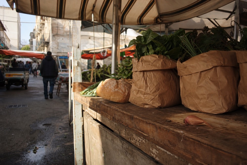 Paper bags of vegetables and bread on a market stall counter in Palermo