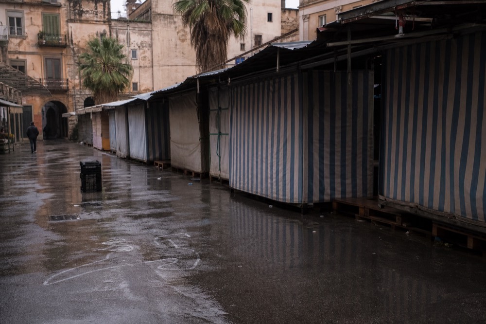 Closed market stalls with shuttered awnings in a Palermo square