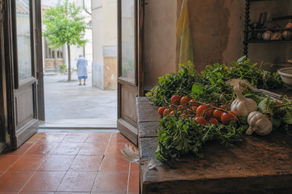 Fresh cooking ingredients laid out on a wooden table in a Sicilian kitchen