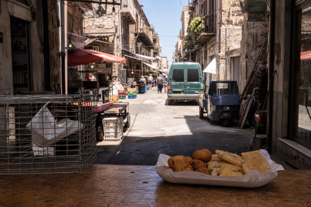 Chickpea fritters and potato croquettes in a paper tray on a market counter