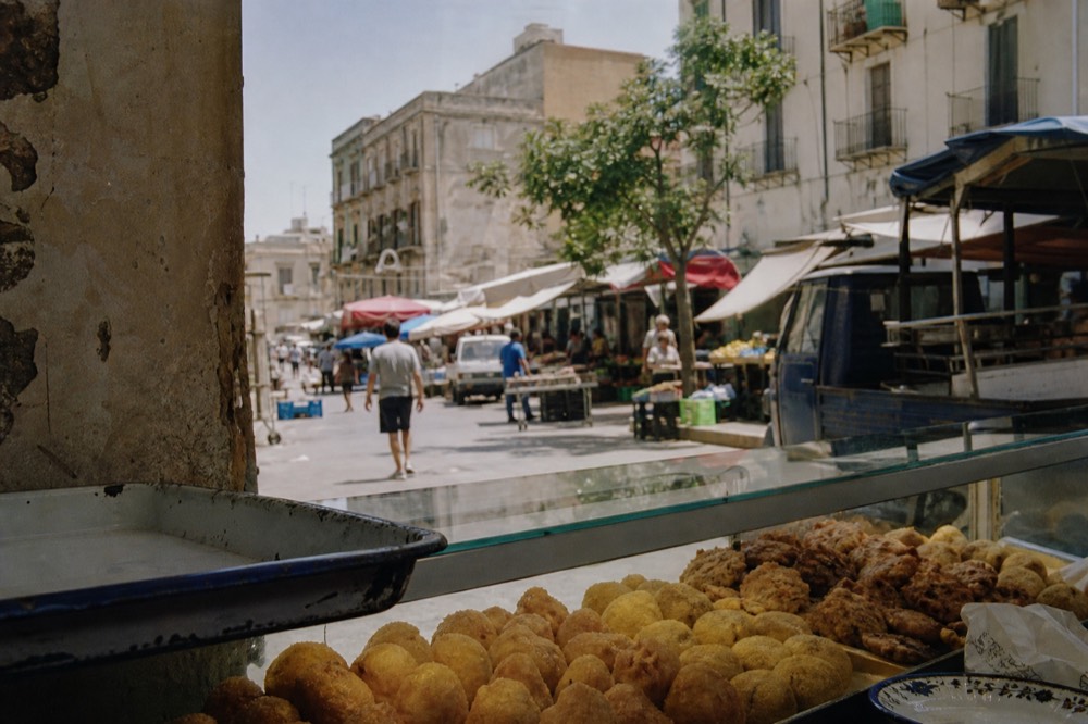 Sicilian rice balls and fried snacks displayed in a glass counter
