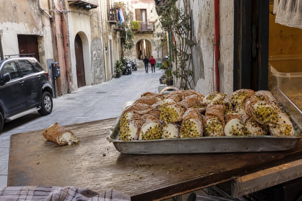 Cannoli filled with ricotta cream and pistachio pieces on a tray