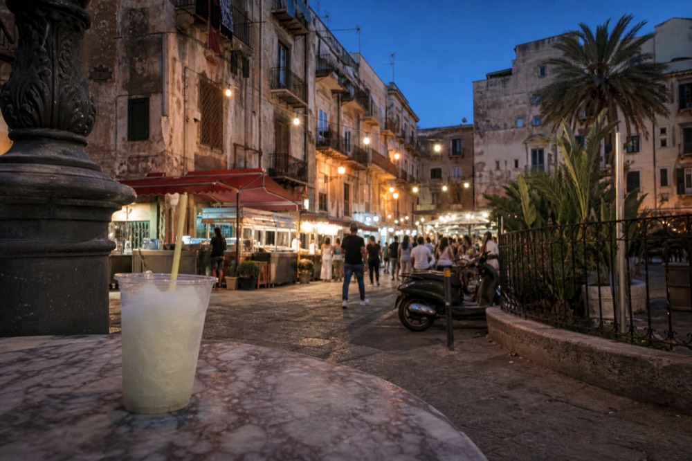 Evening food stalls lit up along a Palermo street with people browsing