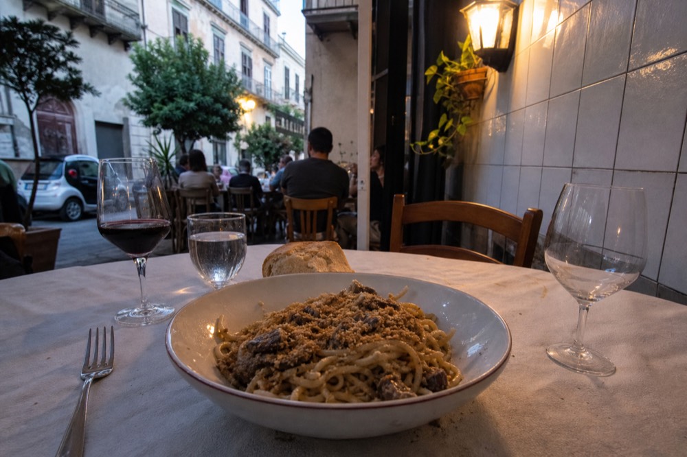 A Palermo trattoria table with pasta, wine and bread during dinner service