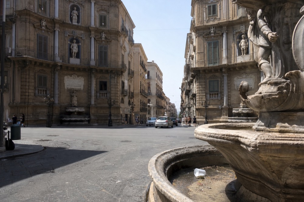 Baroque street corner with ornate fountains and pedestrians in a historic city square