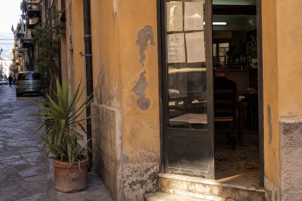A chalkboard menu outside a small Palermo eating house with prices listed