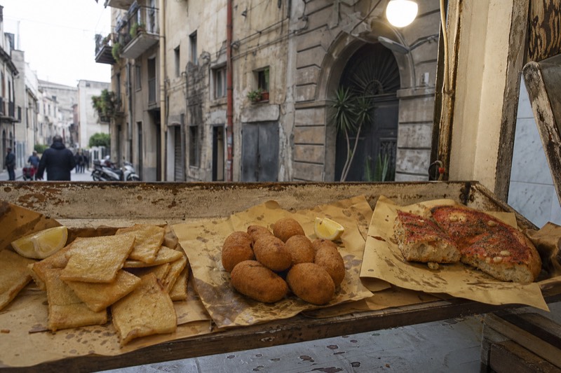 An assortment of Palermo street food laid out on paper on a market counter.